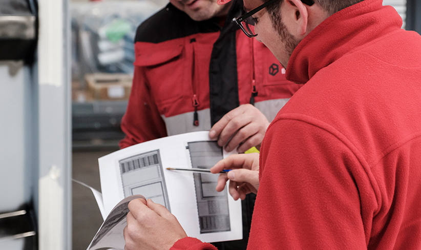 Technicians analyzing blueprints and details of an electrical project in an industrial setting.