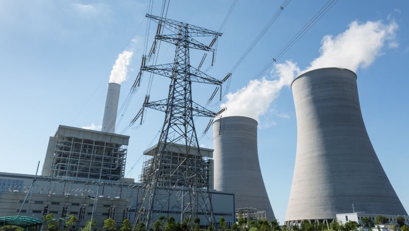 Power generation plant with cooling towers and electrical transmission lines.