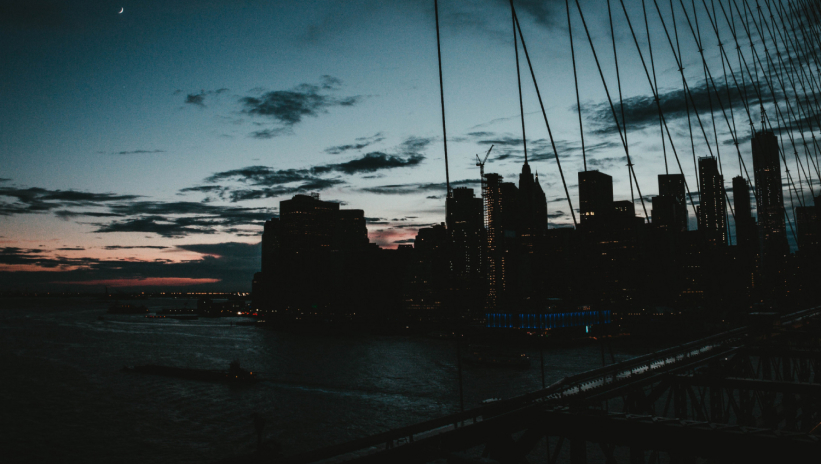 City skyline at dusk during a blackout, with darkened buildings and a partially lit sky.