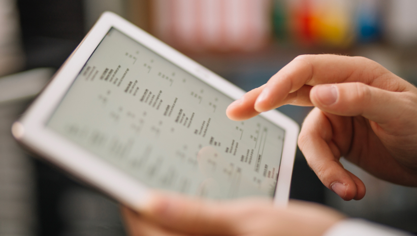 Hand using a tablet with a control or data monitoring interface on the screen.