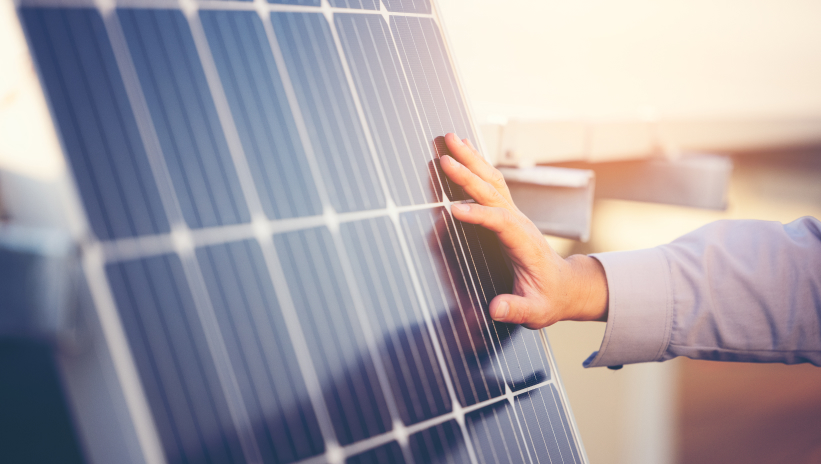 Hand inspecting a solar panel in a solar hybrid system installation.